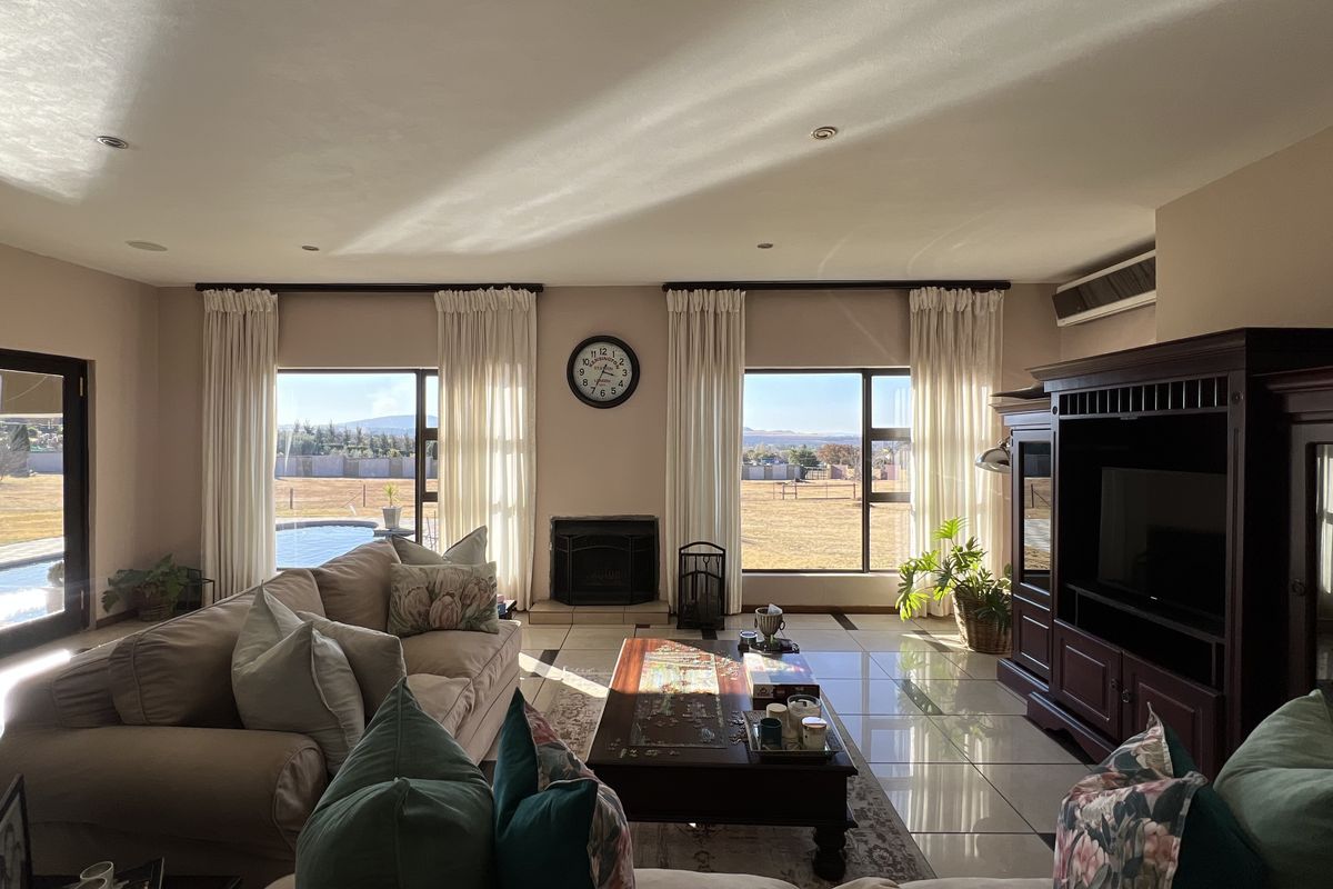 Spacious living room featuring tiled floors, a built-in fireplace, and large windows providing natural light and views of the outdoor area.