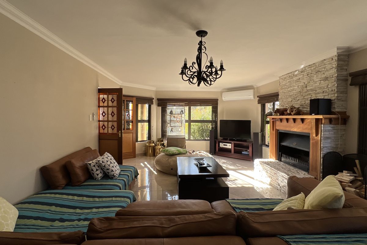 Spacious living room featuring a stone-clad fireplace, tiled flooring, and an air conditioning unit, creating a comfortable and inviting atmosphere.