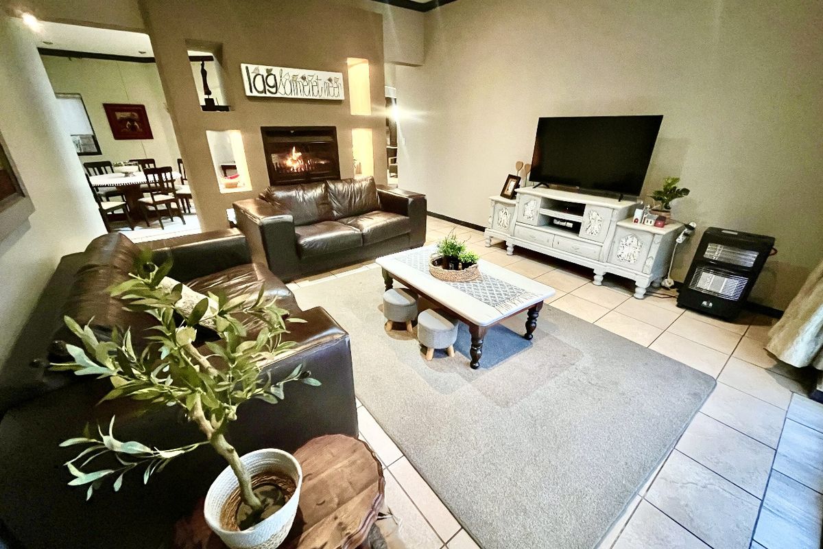 Spacious living room featuring a built-in fireplace with decorative wall niches and neutral tiled flooring, providing a comfortable and functional family space.