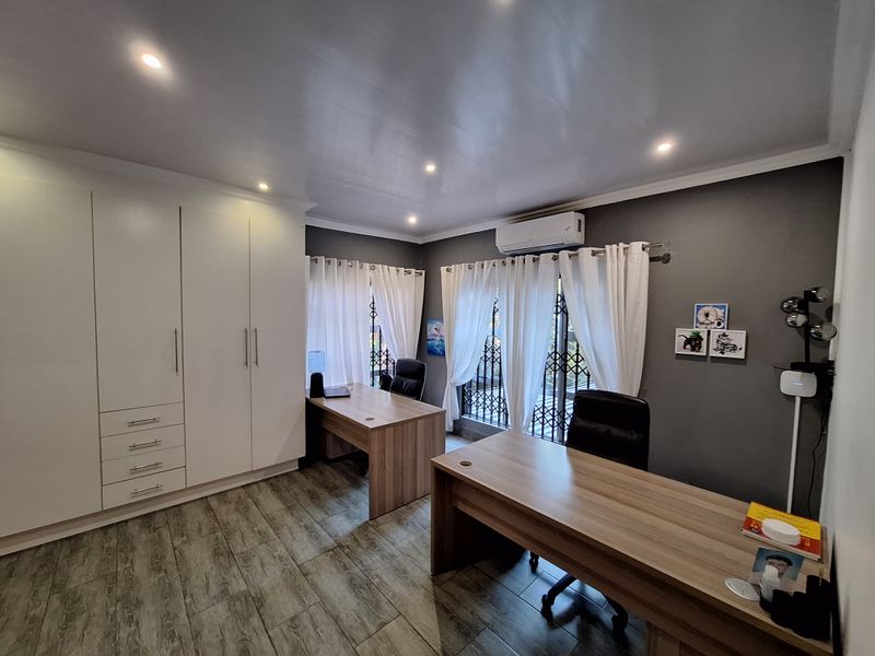 A well-maintained home office featuring built-in cabinetry, tiled flooring, recessed lighting, and a split-system air conditioning unit.