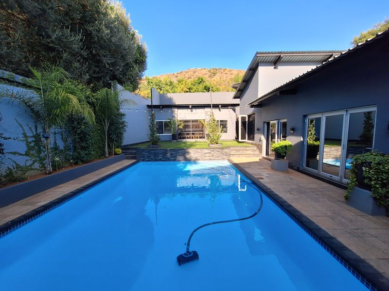 A well-maintained outdoor pool area featuring a clear swimming pool, tiled patio space, and direct access to the home through large sliding glass doors.