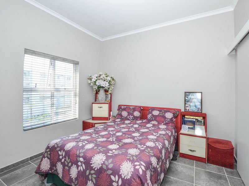A bedroom featuring tiled flooring, neutral walls, coving, and a sliding wardrobe door, providing a functional and well-lit sleeping space.