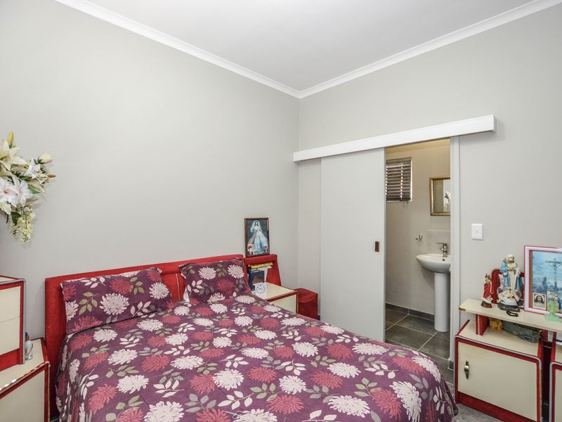 A bedroom featuring neutral walls, coving, and an en-suite bathroom accessed via a sliding door with a pedestal basin.