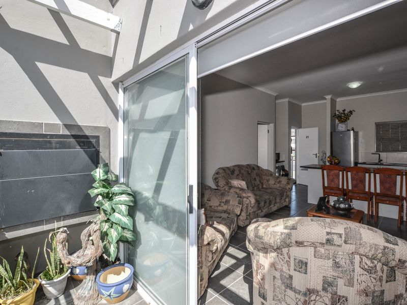Open plan living area featuring tiled floors and a seamless transition to an outdoor patio with a built-in braai.