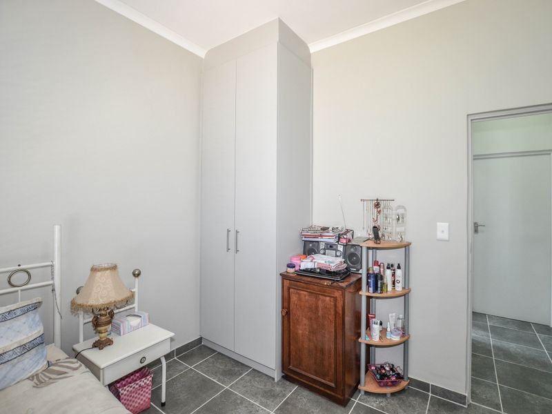 A bedroom featuring neutral wall tones, tiled flooring, and a built-in wardrobe, offering a clean and functional living space.