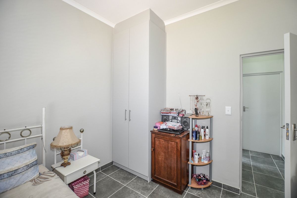 A bedroom featuring neutral wall tones, tiled flooring, and a built-in wardrobe, offering a clean and functional living space.