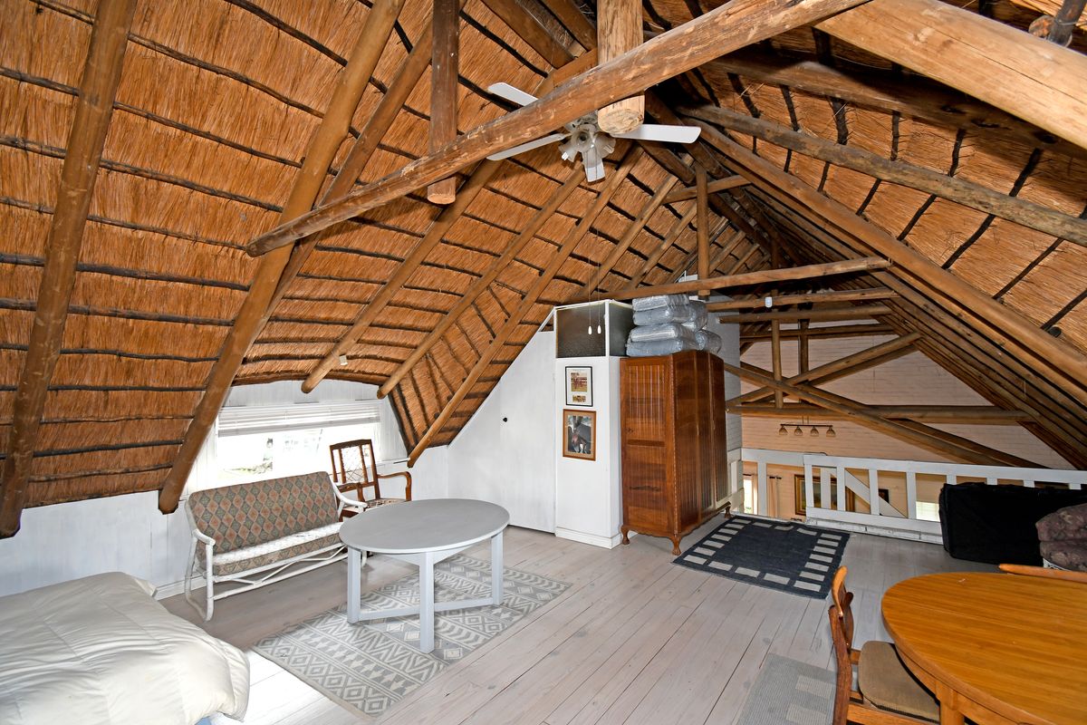 Spacious loft area featuring a traditional exposed thatch roof, timber trusses, and wooden flooring, offering a rustic and open living space.