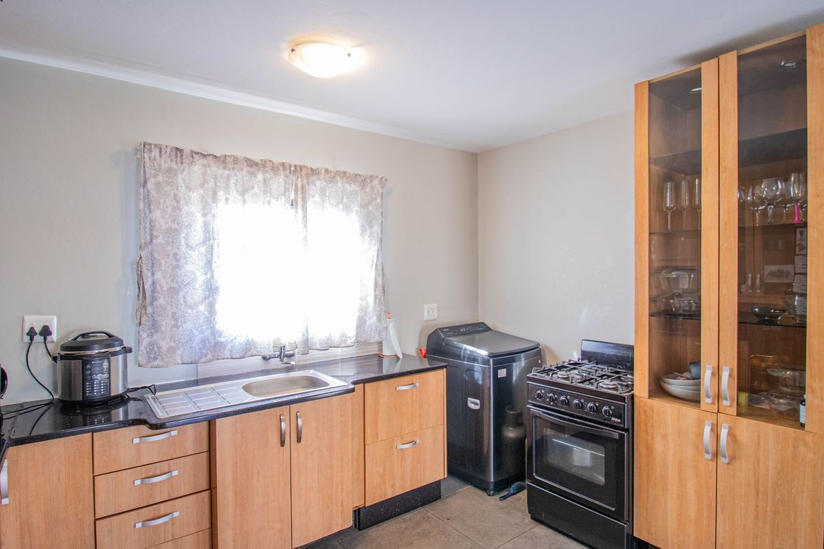 Functional kitchen featuring wood-finish cabinetry, a stainless steel sink, gas stove with oven, and integrated display shelving.