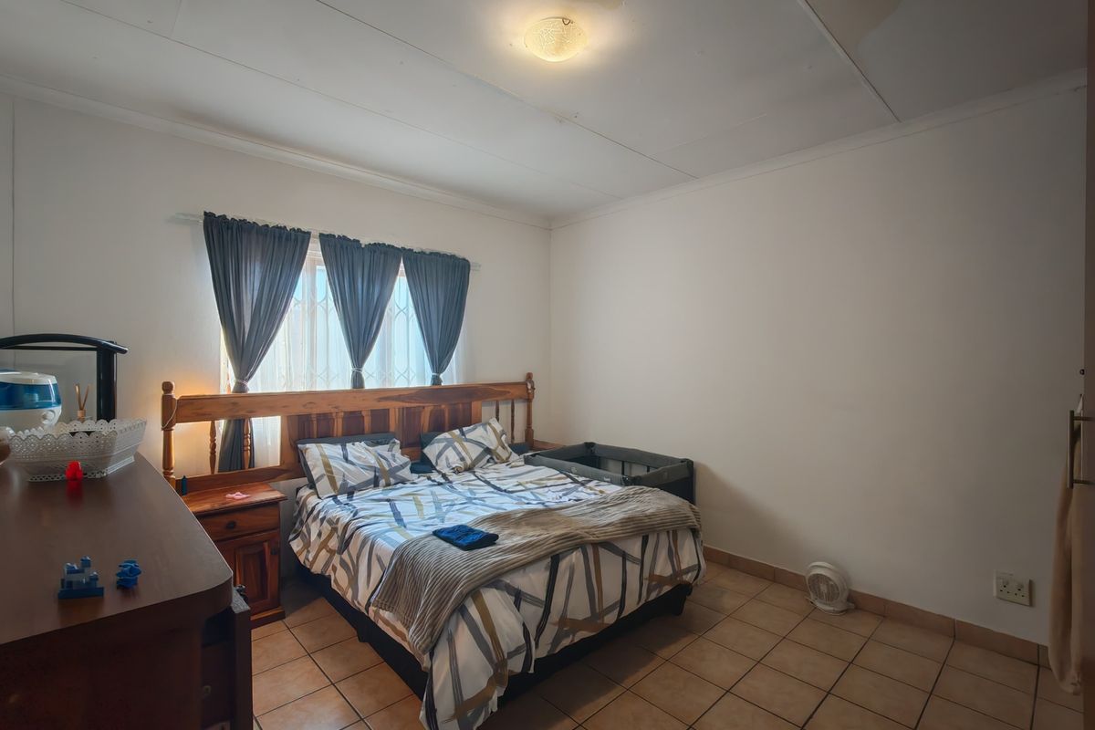 A bedroom featuring tiled flooring and security bars on the window, showing visible water staining on the ceiling.