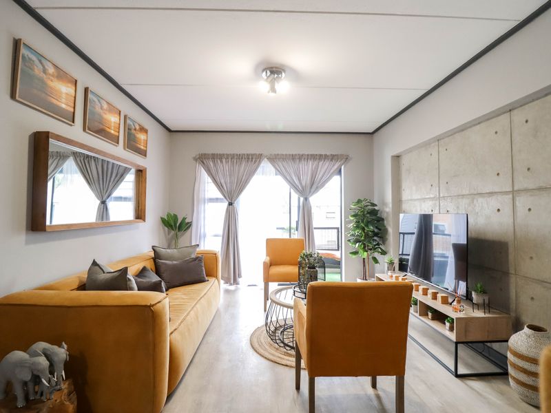 A modern living room featuring an exposed concrete accent wall, laminate flooring, and a sliding glass door leading to an outdoor area.