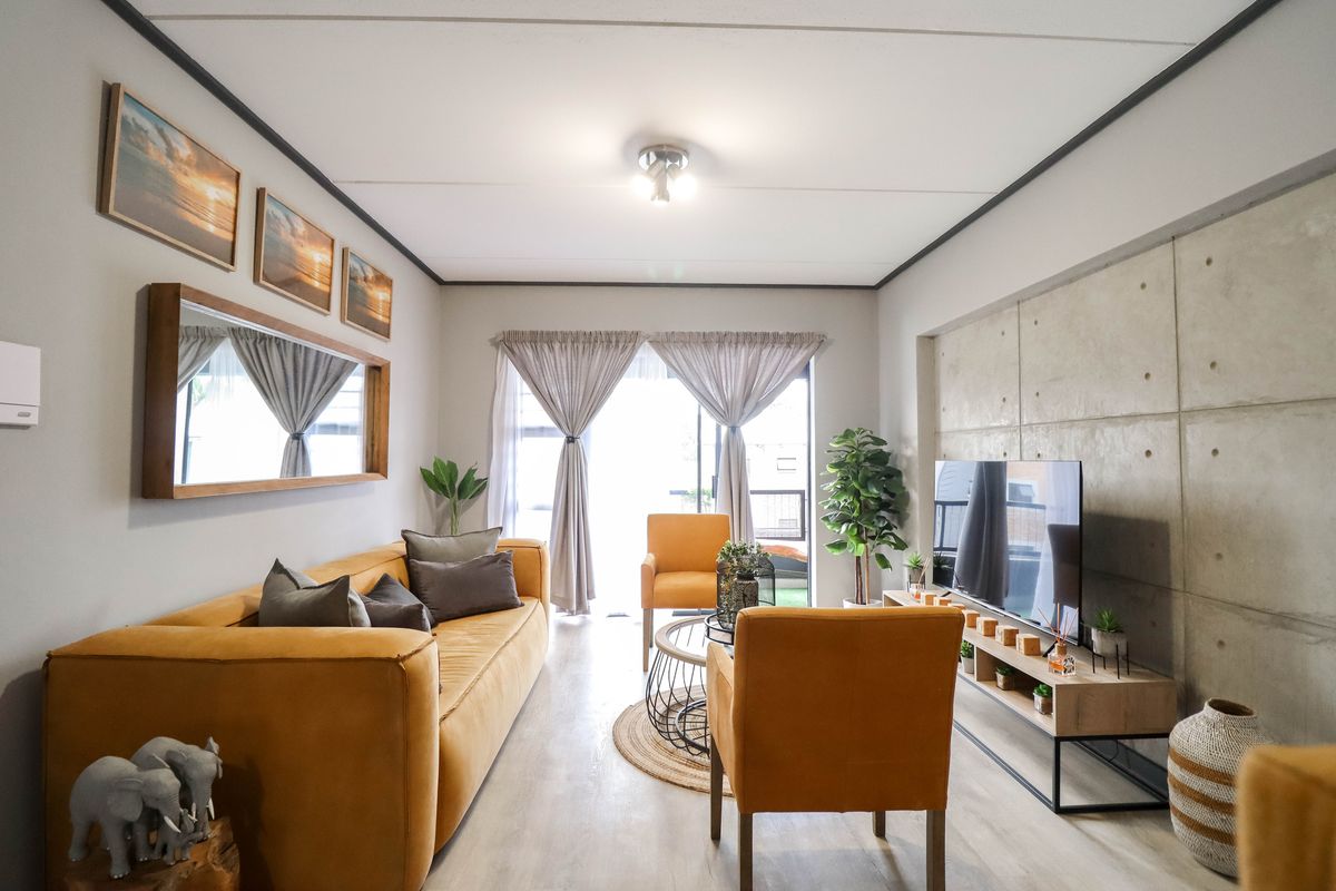 A modern living room featuring an exposed concrete accent wall, laminate flooring, and a sliding glass door leading to an outdoor area.