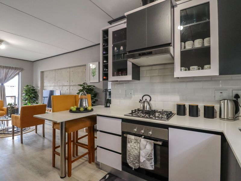 Modern open-plan kitchen featuring sleek cabinetry, quartz countertops, gas hob, and subway tile backsplash, seamlessly flowing into the adjacent living area.