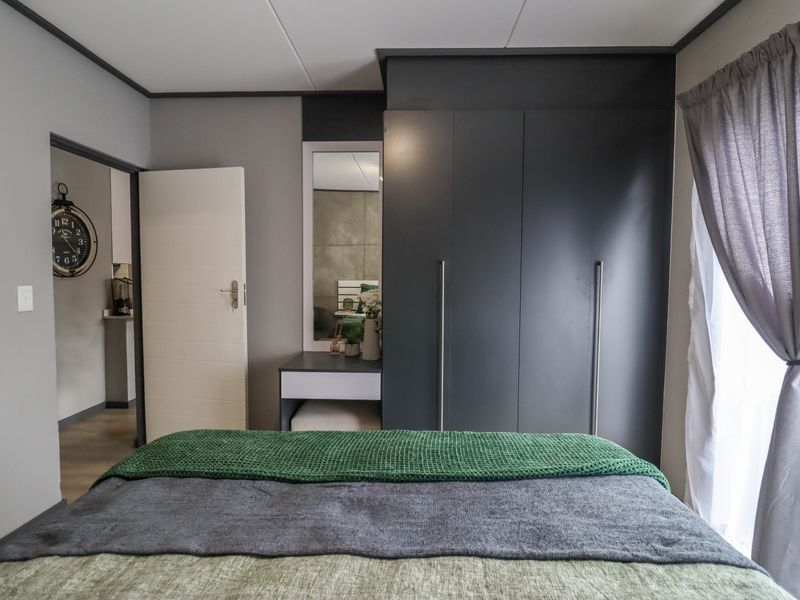 A well-maintained bedroom featuring a modern dark grey built-in wardrobe and integrated vanity unit with clean finishes.