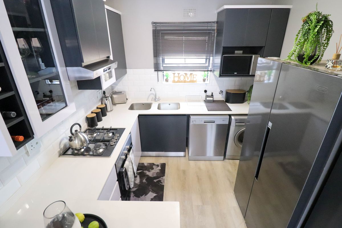 Modern kitchen featuring dark cabinetry, white countertops, subway tile backsplash, gas hob, built-in oven, and integrated space for appliances.