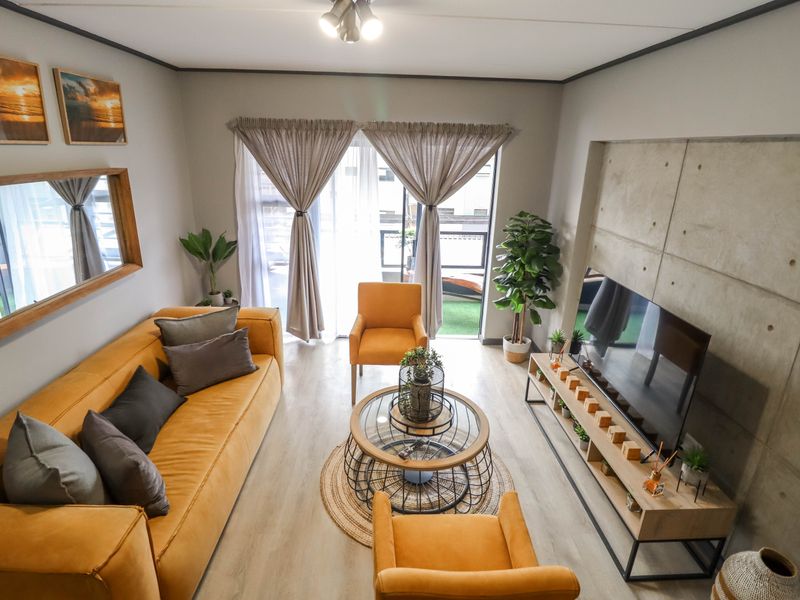 Modern living room featuring a striking concrete feature wall, light laminate flooring, and direct access to a balcony through sliding glass doors.