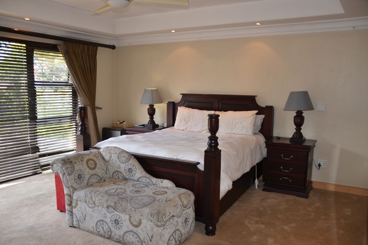 Spacious bedroom featuring a tray ceiling with recessed lighting, a ceiling fan, and large sliding glass doors with venetian blinds leading outdoors.