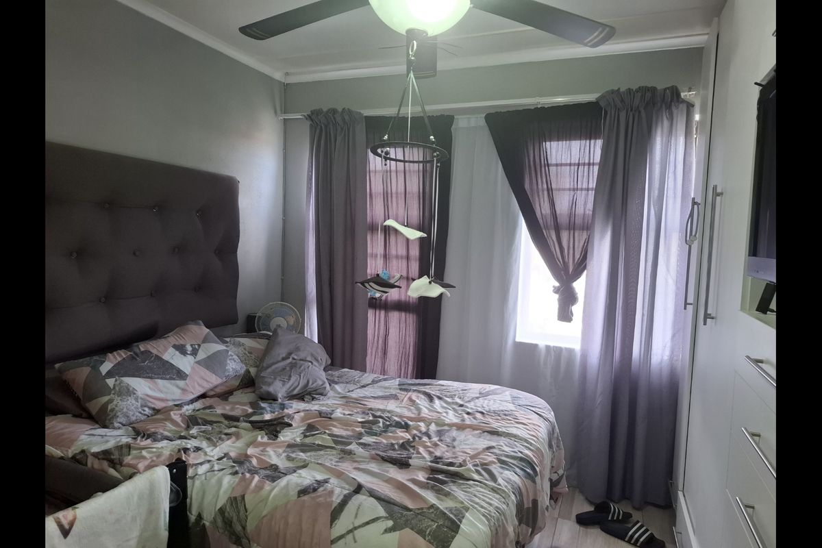 A cozy bedroom featuring a ceiling fan and built-in wardrobe storage, providing functional space and natural light through the window.