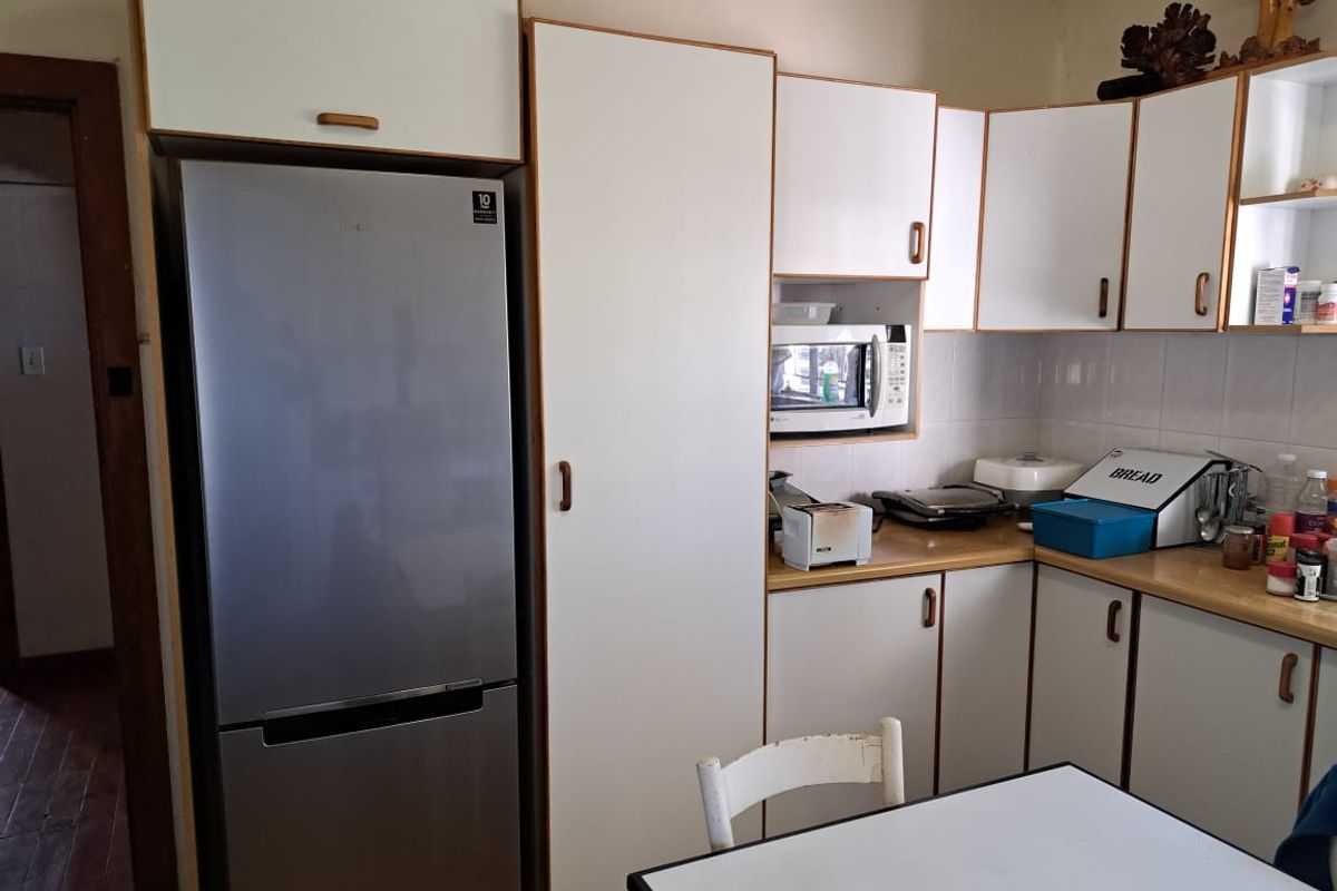 A functional kitchen featuring white cabinetry, laminate countertops, and a built-in microwave space, offering a practical layout for daily meal preparation.