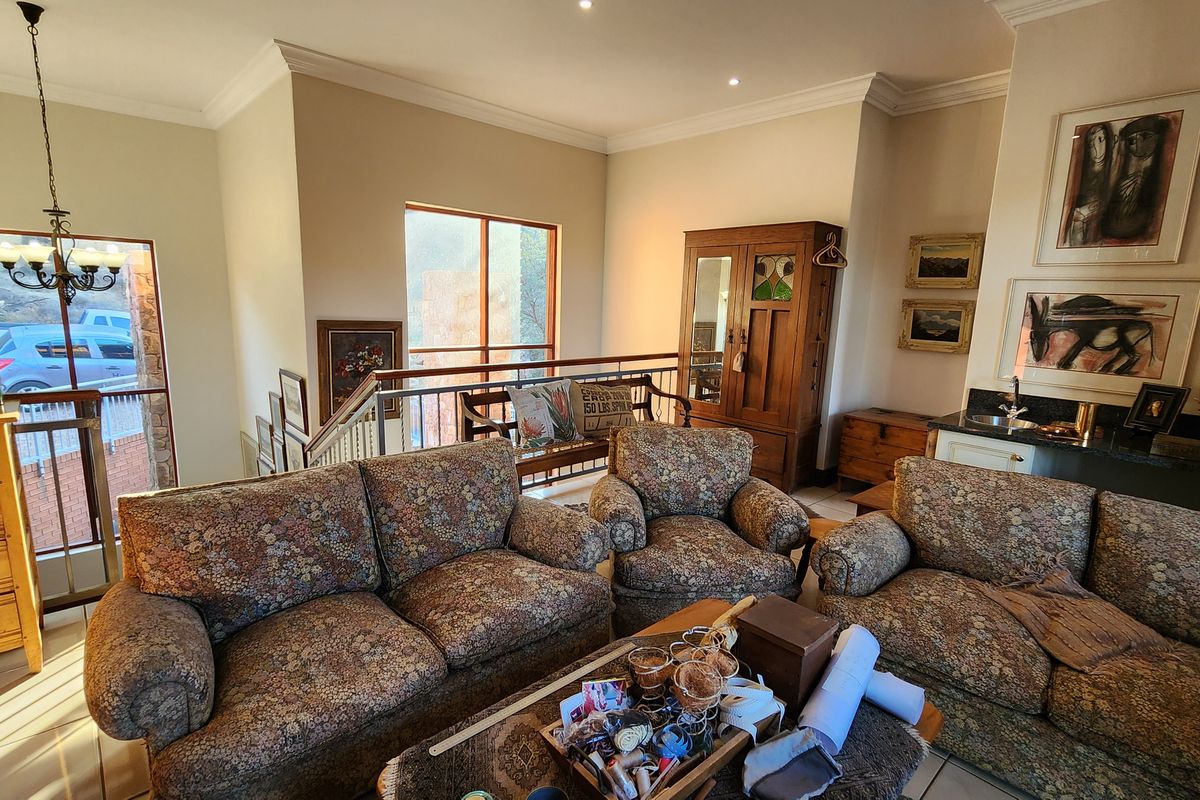 Spacious living area featuring a built-in wet bar, crown molding, and access to an internal staircase with a metal railing.