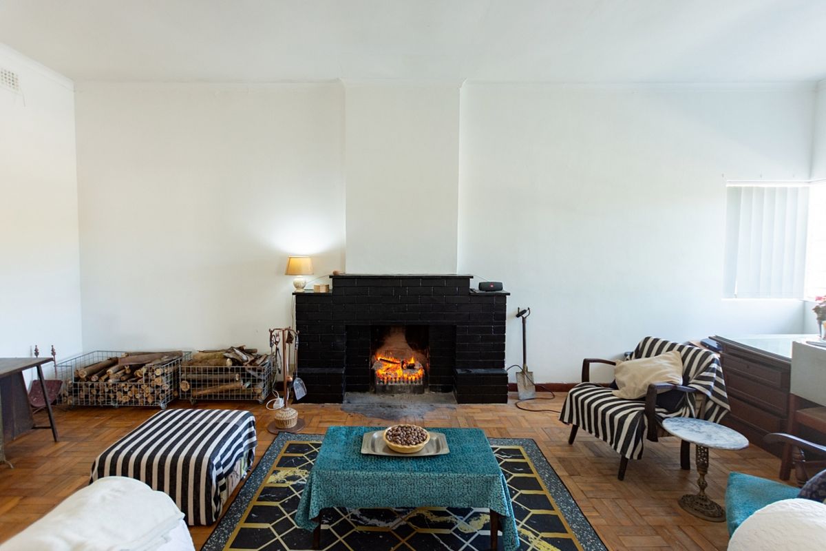 A cozy living room featuring a prominent black brick fireplace and classic parquet flooring, offering a warm and inviting atmosphere.