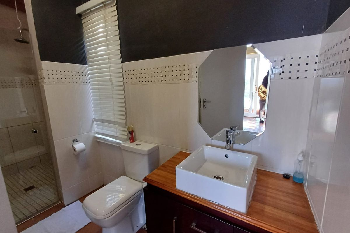 A functional bathroom featuring a modern vessel sink on a wooden vanity, a separate shower enclosure, and tiled wall finishes.