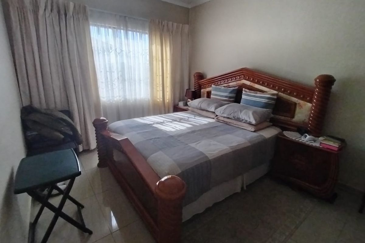 A standard bedroom featuring tiled flooring and large windows with curtain rails, offering a functional space with neutral wall finishes.
