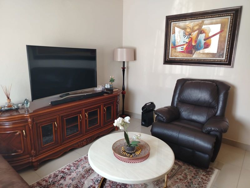 A comfortable living room area featuring neutral wall tones and tiled flooring, providing a functional space for relaxation.