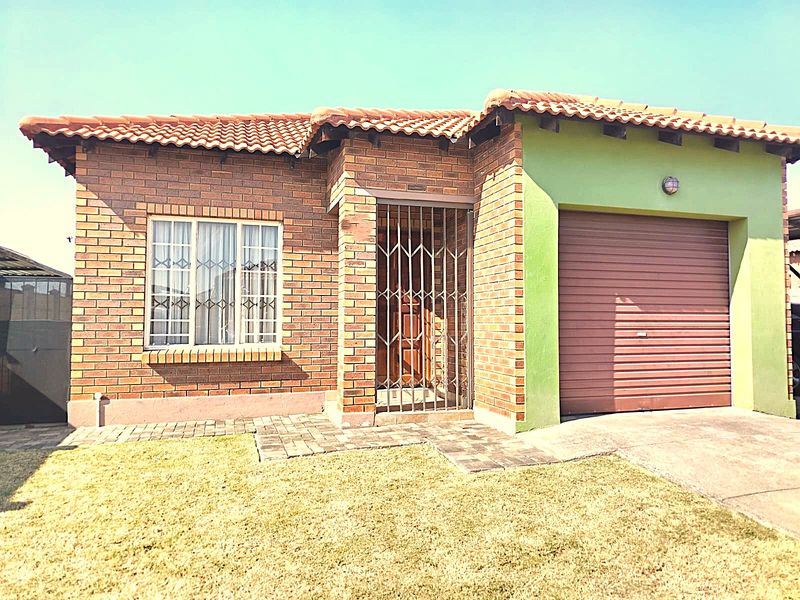Front elevation of a face brick house featuring a tiled roof, integrated garage with roller door, and secure entrance with security gate.