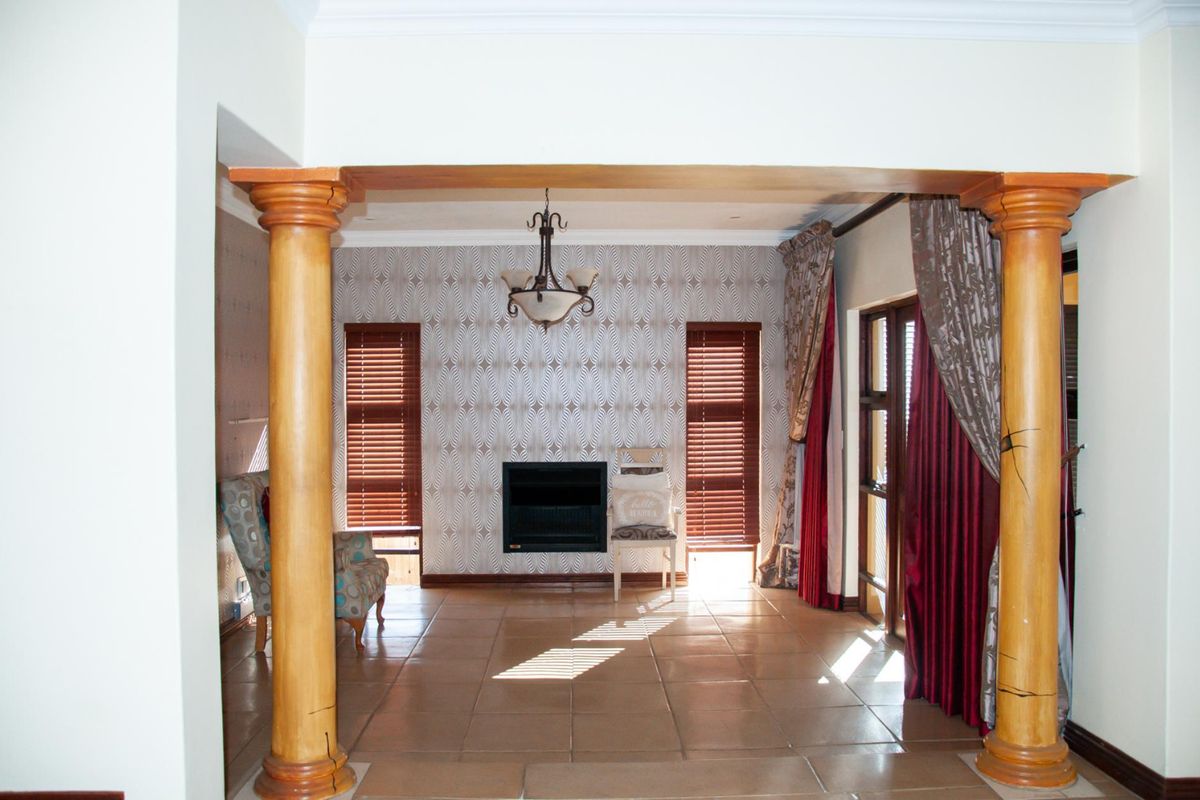 Spacious living area featuring a built-in fireplace, tiled flooring, and decorative columns, creating a distinct architectural focal point.