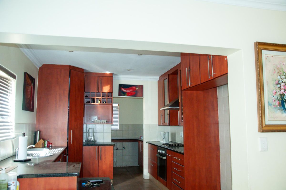 A functional kitchen featuring dark wood cabinetry, granite countertops, a built-in oven, and a hob with an extractor fan.