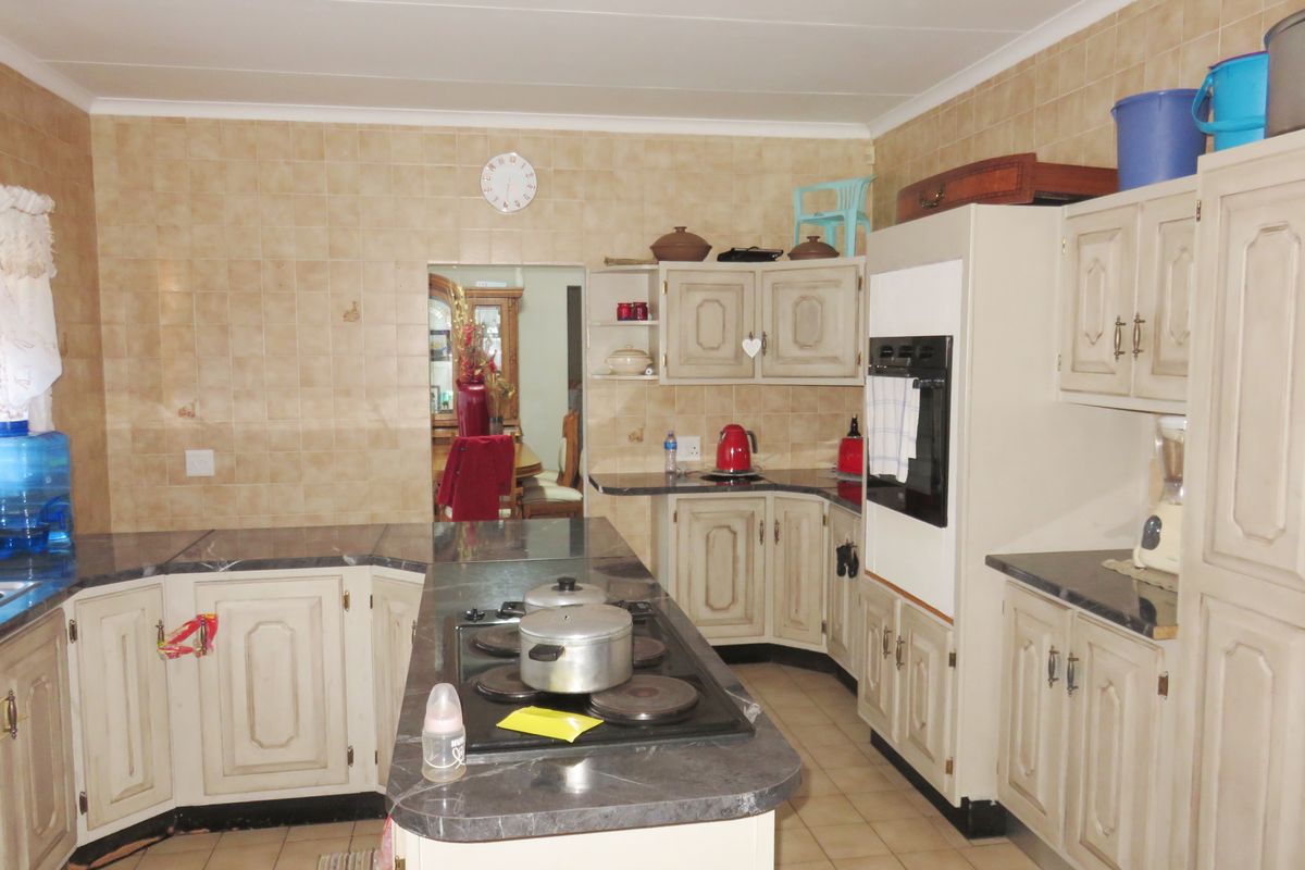 A functional kitchen featuring a central island with a built-in hob, ample cabinetry, and tiled wall finishes.