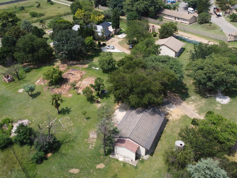 Aerial view of a spacious small holding property featuring a tennis court, swimming pool, multiple outbuildings, and extensive landscaped grounds.