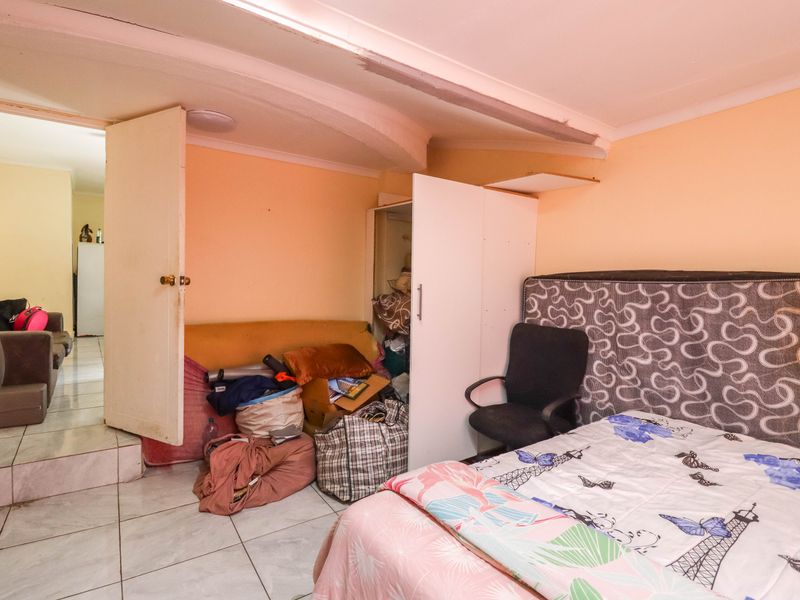 A bedroom featuring tiled flooring and a built-in cupboard, showing signs of wear and requiring cosmetic updates to improve the overall condition.