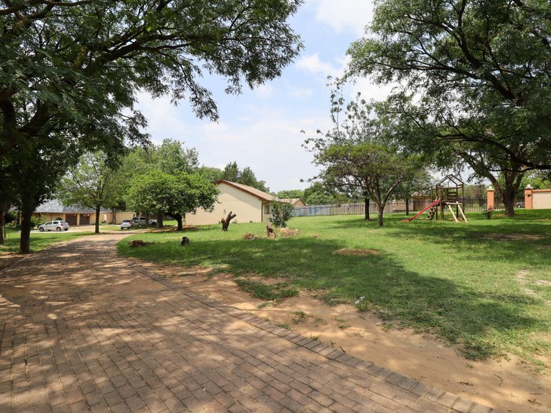 Spacious garden area featuring a paved driveway, mature trees, and established lawn on a small holding property.