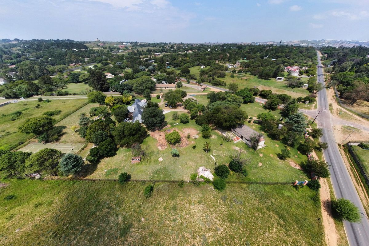 Aerial view of a spacious small holding property featuring mature landscaping, a private tennis court, and extensive grounds with direct road access.