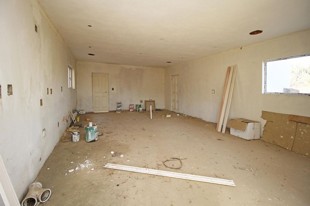 An unfinished interior space featuring bare walls, exposed ceiling cutouts, and concrete flooring, presenting a blank canvas for renovation and custom finishing.