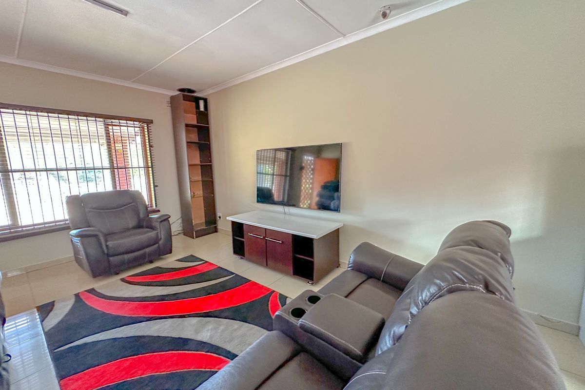 A living room featuring tiled flooring, security bars on the windows, and a neutral wall finish.