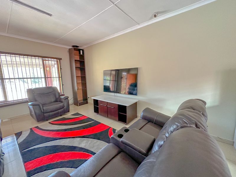 A living room featuring tiled flooring, security bars on the windows, and a neutral wall finish.