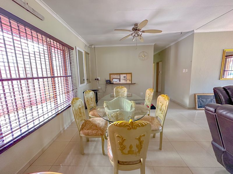 A dining area featuring tiled flooring, a ceiling fan, and a convenient pass-through window connecting to the kitchen space.