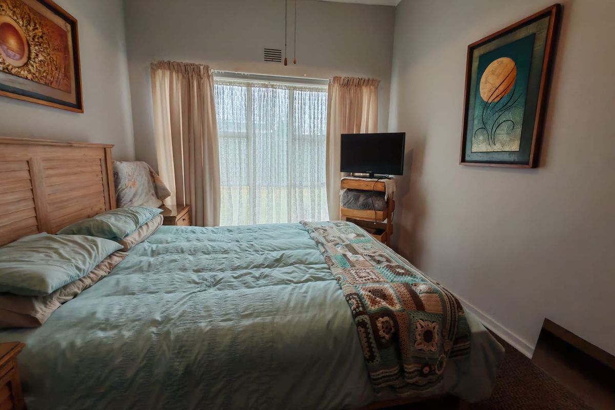 A functional bedroom featuring neutral wall finishes, a window with curtain treatments, and a ceiling ventilation point.
