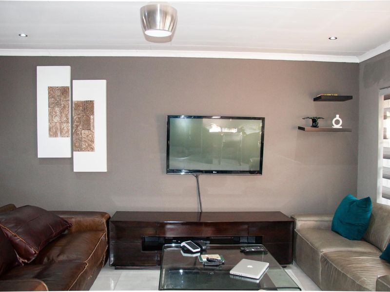 A living room featuring a dark feature wall, tiled flooring, and recessed ceiling lighting, providing a functional space for relaxation.