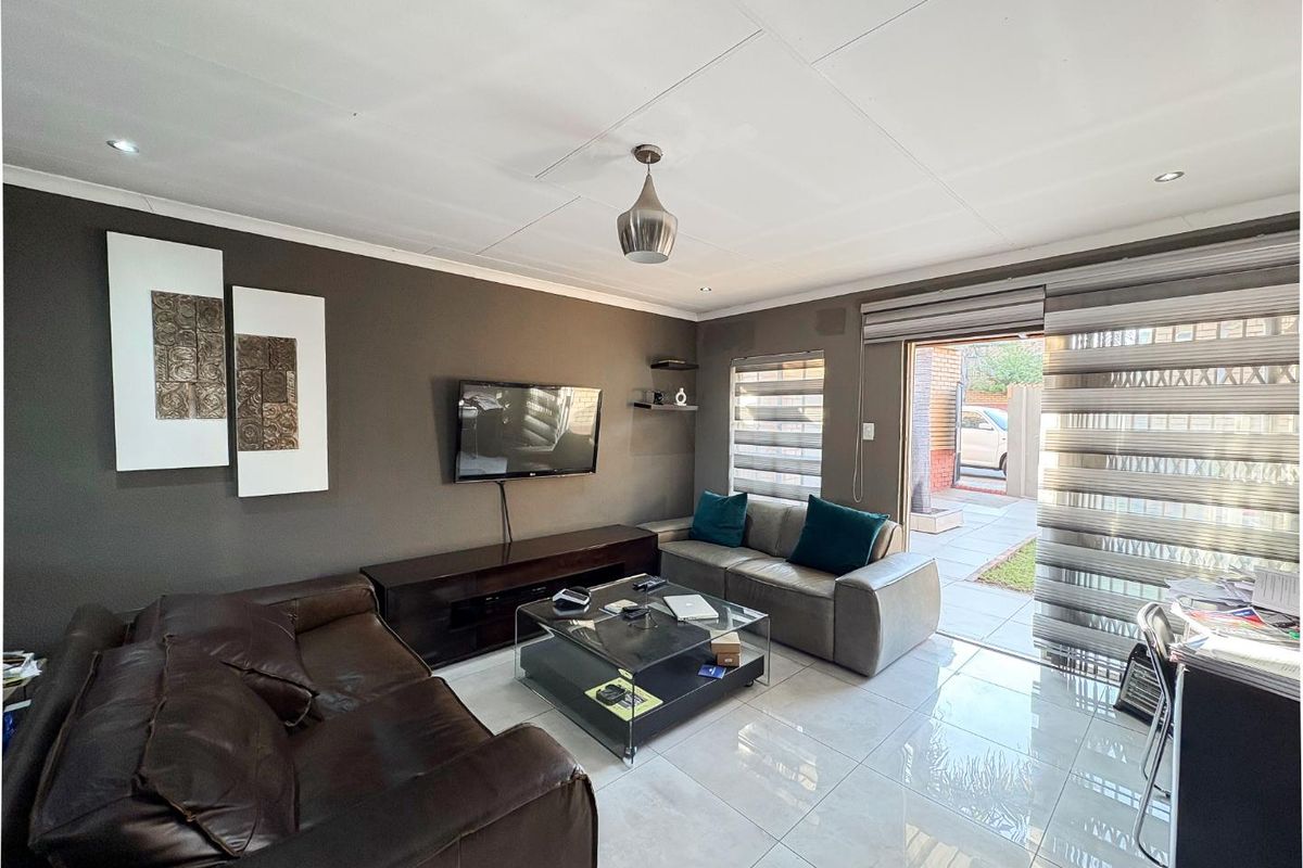 A modern living room featuring large format floor tiles, recessed downlighting, and a sliding glass door providing direct access to the exterior patio area.