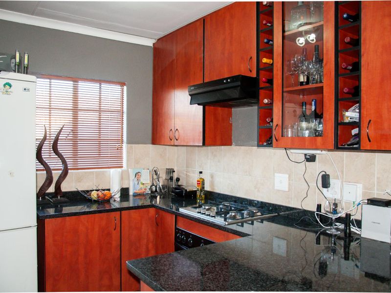 A functional kitchen featuring dark granite countertops, wood-veneer cabinetry, a built-in gas hob, and an integrated extractor fan.