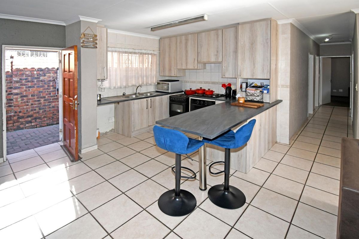 Functional kitchen featuring light wood-look cabinetry, a breakfast bar, tiled flooring, and direct access to an outdoor area.