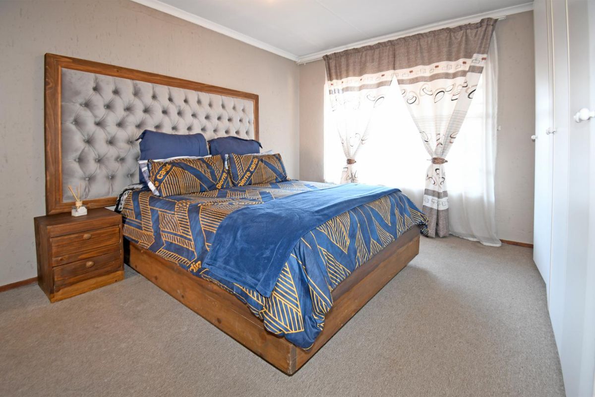 A bedroom featuring neutral wall tones, carpeted flooring, and built-in wardrobe storage.