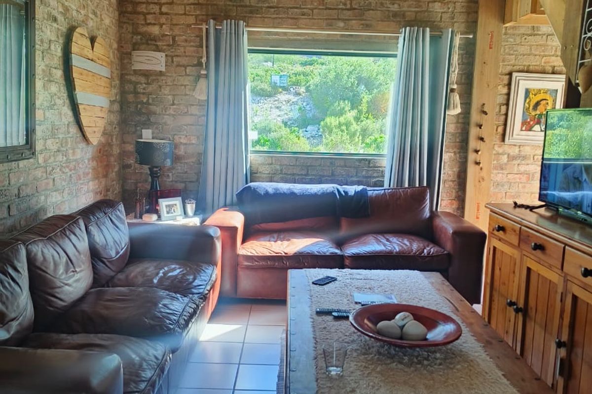 A rustic living room featuring exposed brick walls and timber ceiling beams, creating a warm and character-filled atmosphere with natural light.