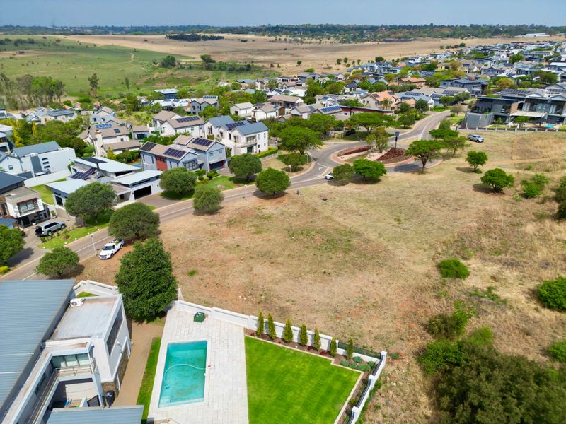 Aerial view of a residential vacant land plot featuring a swimming pool, paved patio area, and established lawn within a suburban estate.