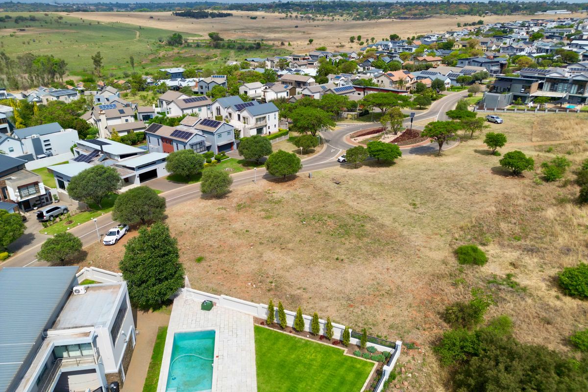 Aerial view of a residential vacant land plot featuring a swimming pool, paved patio area, and established lawn within a suburban estate.