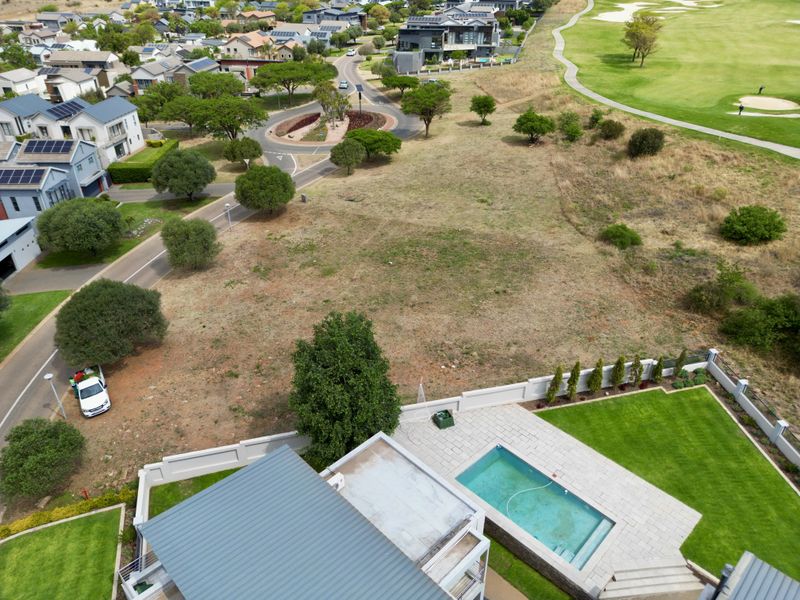 Aerial view of a residential vacant plot adjacent to a golf course, featuring a private swimming pool, paved patio area, and established boundary walls.