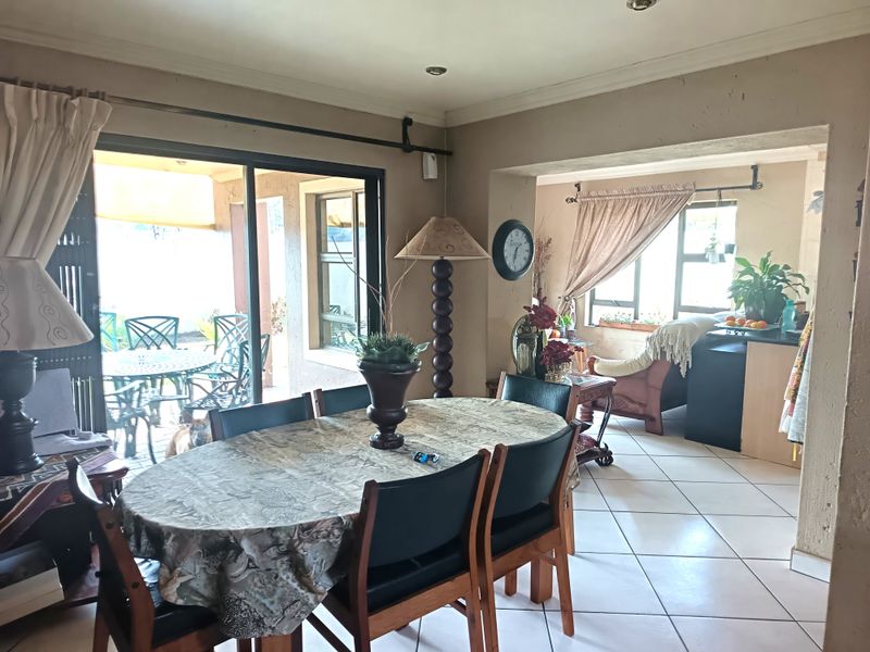 Open-plan living and dining area featuring tiled flooring, recessed lighting, and large sliding glass doors providing access to the outdoor patio.
